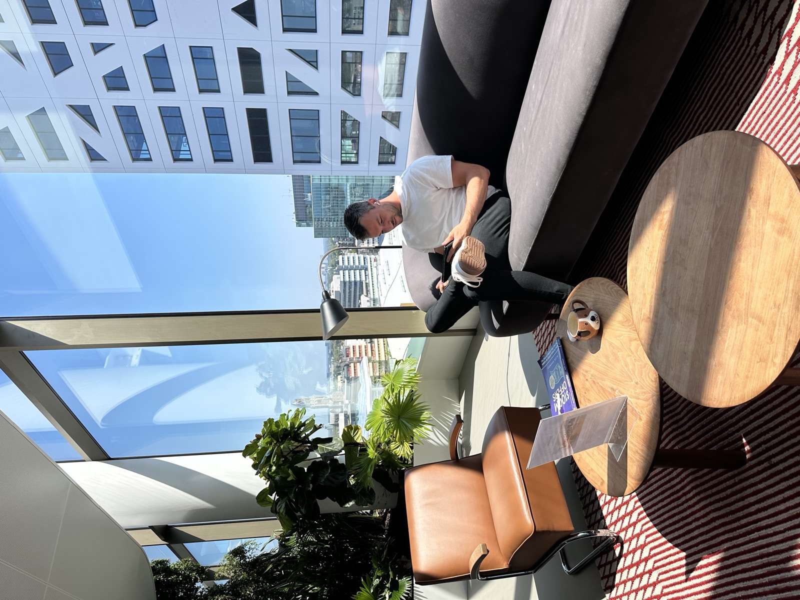 Mario sitting with a coffee in a bright city workspace